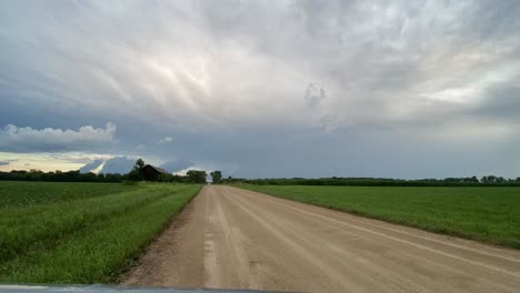 timelapse-of-clouds-in-the-fields-country-side-of-minnesota-with-a-dirt-road-in-frame-on-summer-time,-cloudy-day