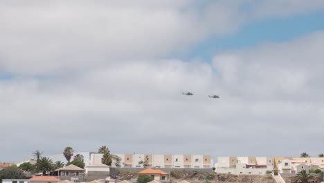 Slow-motion-shot-two-military-helicopters-flying-over-residential-area,-Porto-Santo