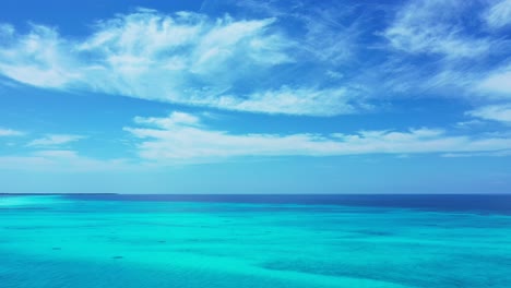 Vivid-colors-of-seascape-wallpaper-with-frozen-clouds-on-bright-blue-sky-over-ocean-horizon-and-shiny-turquoise-lagoon-in-Antigua,-copy-space