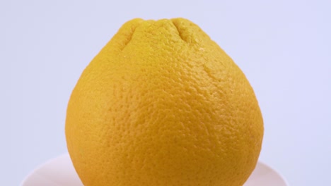 Nahaufnahme-Von-Frischem-Valencia-Orange-Mit-Weißem-Hintergrund,-Flachem-Fokus-Und-Langsamer-Rotation