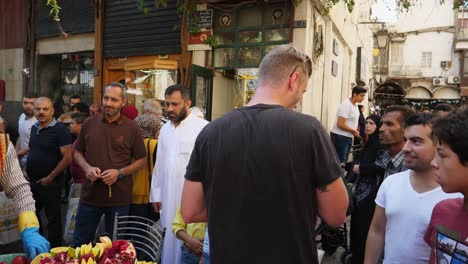 Selling-juice-at-a-bazaar-in-Damascus,-tourist-getting-his-licorice-drink