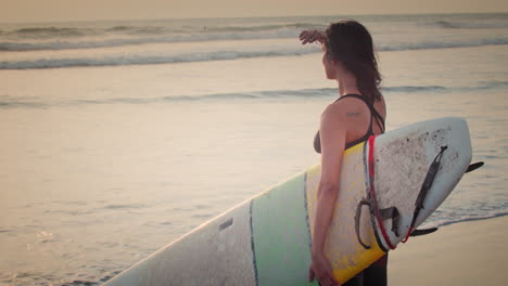 Professional-Female-Surfer-Watching-Confidently-at-the-Sunset-Holding-Surf-Board-at-the-Beach
