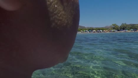 POV-follow-shot-of-caucasian-kid,-preparing-to-dive-into-sea,-holding-a-swim-board-and-wearing-swim-suit-and-sea-googles-60fps