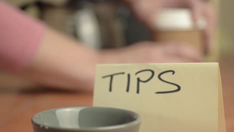 Tipping-bowl-in-cafe-with-person-getting-coffee-in-background