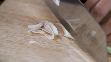 Cutting-Lemongrass-into-small-Slices-with-Knife-on-Wooden-Cutting-Board---Close-Up