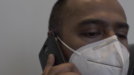 Erwachsener-Asiatischer-Mann-Mit-N95-Gesichtsmaske-Drinnen,-Der-Mit-Dem-Mobiltelefon-Spricht