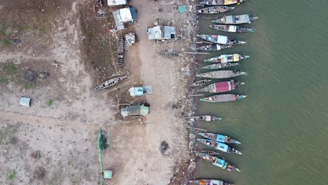 Aerial-top-down-shot-showing-fishing-boats-parking-on-deck-beside-ghetto-poor-quarter-in-Phnom-Penh