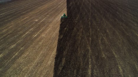 4k-aerial-shot-of-drone-panning-up-to-reveal-a-tractor-disking-across-a-field