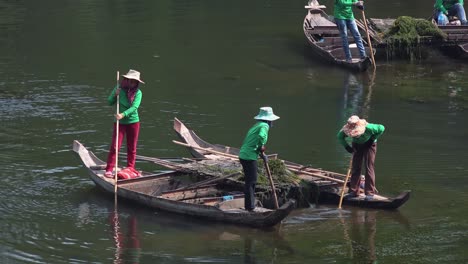 Close-Shot-of-Asian-Ladies-in-Boats-Cleaning-the-Moat-Around-Angkor-Wat-in-Cambodia