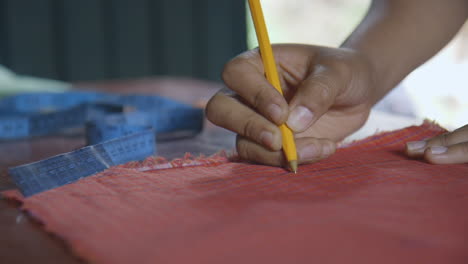 A-woman's-hand-drawing-an-outline-on-some-cloth-to-create-an-apron-in-Oaxaca,-Mexico
