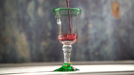 Seamless,-looping-clip-of-red-wine-pouring-into-a-rustic-glass-with-blue-background