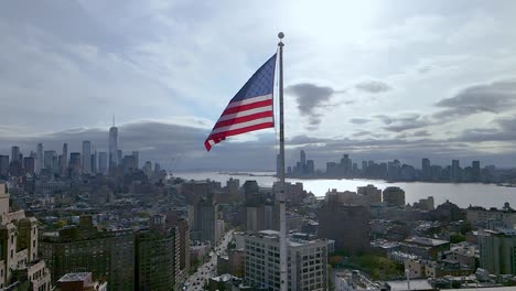 Luftaufnahmen-In-Zeitlupe-Mit-Der-Flagge-Der-USA,-Die-Im-Wind-Weht,-Mit-New-York-City-Im-Hintergrund