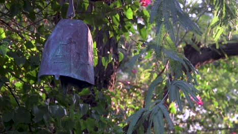 Close-up-of-a-metal-garden-bell-hanging-in-a-desert-mesquite-tree