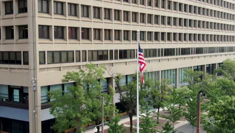 American-flag-at-US-government-building,-courthouse,-business-office,-skyscraper-in-urban-city-setting
