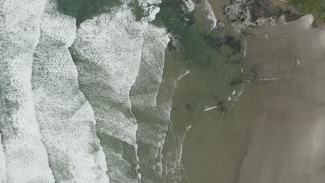 Stationary-overhead-drone-shot-of-ocean-waves-coming-into-beach
