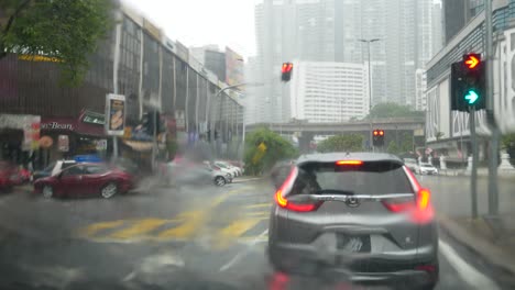 The-view-from-inside-the-car,-the-atmosphere-of-heavy-rain-at-the-intersection-of-traffic-light