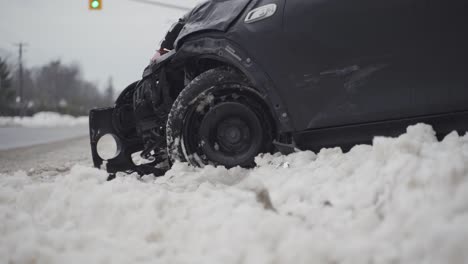 Damage-to-a-crashed-car-on-the-side-of-a-snowy-road