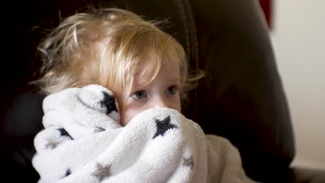 Baby-girl-watching-television-wiht-messy-hair-and-holding-her-security-blanket---close,-isolated-portrait