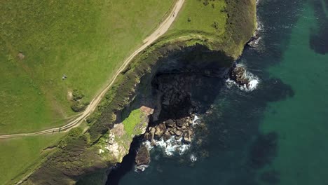 Waves-splashing-on-the-rocks-by-the-coastal-walk-of-Port-Isaac-Village-in-England--aerial