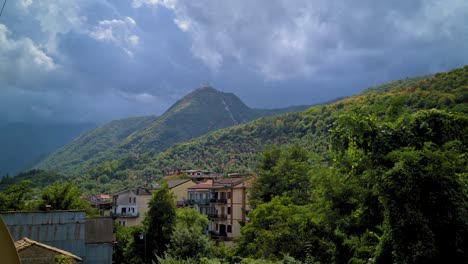 Town-hidden-in-mountain-woods,-contrasting-day-light-and-clouds,-Montello,-Italy