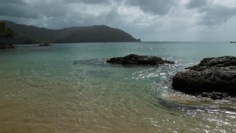 Beautiful-shot-of-waves-pushing-up-onto-the-sandy-shores-of-Pirates-Bay,-Tobago