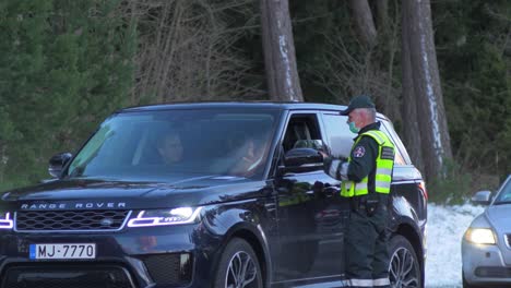 Lithuanian-border-guard-officer-control-passenger-SUV-car-at-the-Lithuania---Latvia-border-during-crisis-measures-in-the-fight-against-the-novel-coronavirus-Covid-19,-medium-shot-from-a-distance