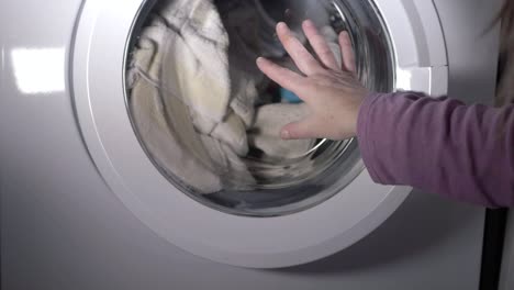 Woman-closing-door-of-washing-machine-medium-shot