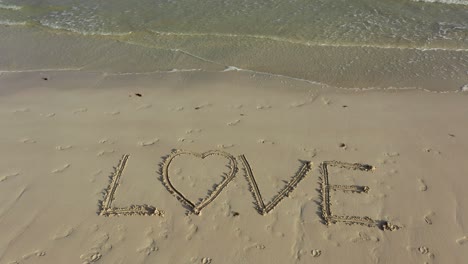 A-turning-shot-of-LOVE-inscribed-in-the-sand-on-a-beach