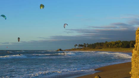 A-group-of-people-engaged-in-kitesurfing-in-sunny-autumn-day,-high-waves,-Baltic-Sea-Karosta-beach-in-Liepaja,-wide-shot