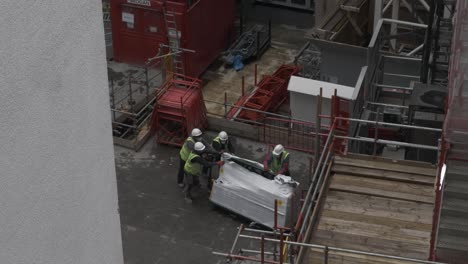 Workers-Loading-Materials-Into-Construction-Site-Elevator-In-Millbank