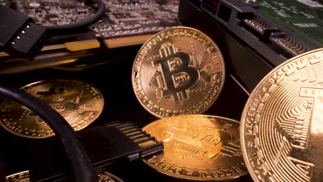 reverse-moving-macro-view-of-golden-bitcoins-with-a-graphics-card-and-hard-drive,-cryptocurrency-mining