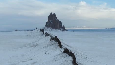 4k-Aerial-tracking-shot-of-Shiprock-Monument,-covered-in-snow,-in-New-Mexico,-USA