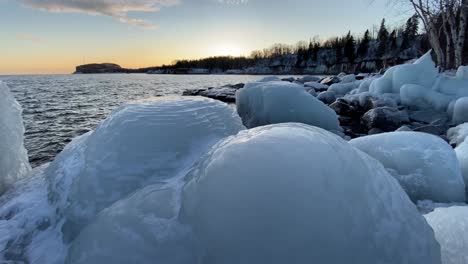 big-chunks-of-ice,-rocks-covered-on-ice-on-lake-superior-shore-line,-sunset