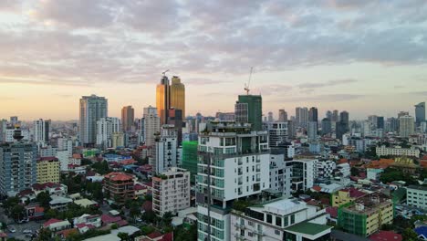 Golden-Tower-And-High-rise-Buildings-In-Downtown-Phnom-Penh,-Cambodia-At-Sunset---aerial