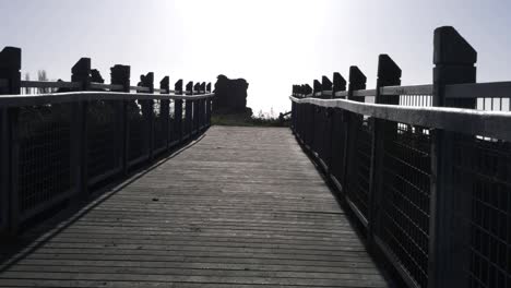 Walking-across-empty-wooden-bridge-wide-zoom-shot