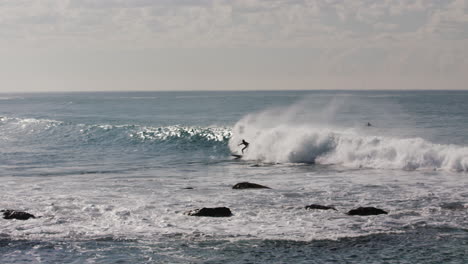 Ein-Surfer-Erwischt-Eine-Schöne-Welle-Vor-Der-Küste-Australiens-Und-Wird-Von-Der-Tünche-Vor-Den-Felsen-Verschluckt