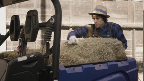 Man-working-loading-the-hay-on-the-box-of-his-off-road-vehicle-to-feed-the-animals