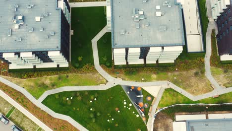 Drone-overhead-push-down-Shot-of-area-in-the-middle-of-a-residential-building-with-cars,-children's-playground-and-parking-for-cars-in-the-house-courtyard