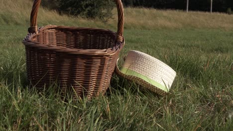 Straw-hat-and-woven-basket-left-in-the-grass-zoom-out-shot