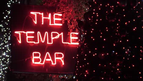 Still-shot-of-a-bar-singe-in-red-neon-lights-with-some-Christmas-decorations-around-it