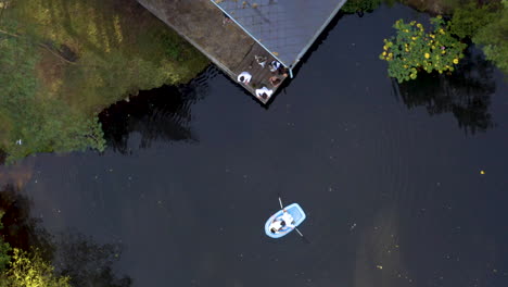 Newlywed-couple-on-a-small-boat-on-a-forest-lake-by-a-cottage,overhead