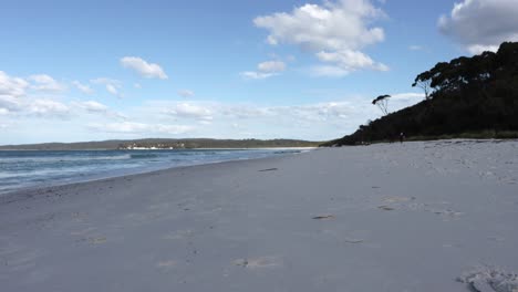 Hyams-Beach-on-a-calm-cloudy-afternoon-with-two-people-approaching,-Locked-shot