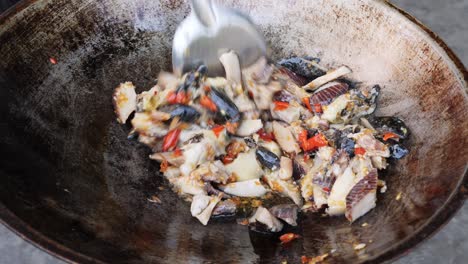 Close-up-shot-stirring-Giant-Sea-Snail-with-sauteed-ingredients-on-Wok