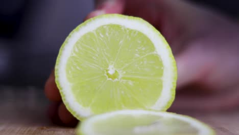 Lemon-being-sliced-with-a-knife-on-a-wooden-chopping-board