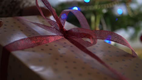 Hands-holding-out-a-gift-wrapped-with-a-red-bow-close-up-shot