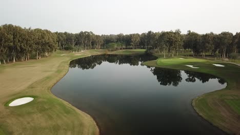 Massive-blue-water-pond-in-middle-of-golf-course-field-in-aerial-shot