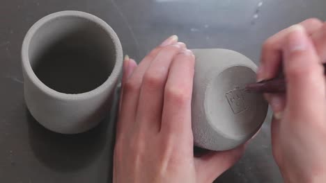 POV-of-Female-Potter-Artist-Carving-signature-on-a-cup'-bottom-surface