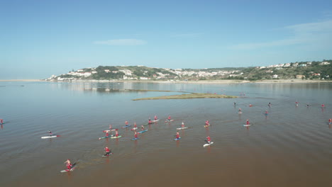Men-Wearing-Santa-Claus-Clothing-In-Stand-Up-Paddle-Boarding-Adventure-During-Holidays-In-Obidos-Lagoon,-Portugal
