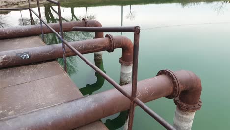 abandoned-and-rusted-water-pumping-dock-in-a-green-body-of-water