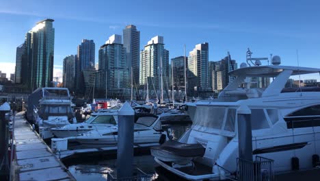 Luxury-pleasure-yachts-moored-at-frozen-jetty's-on-a-cold-sunny-winter-day-with-skyscrapers-build-with-glass-on-the-background